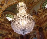 Lots of glass on huge chandelier in very ornate room